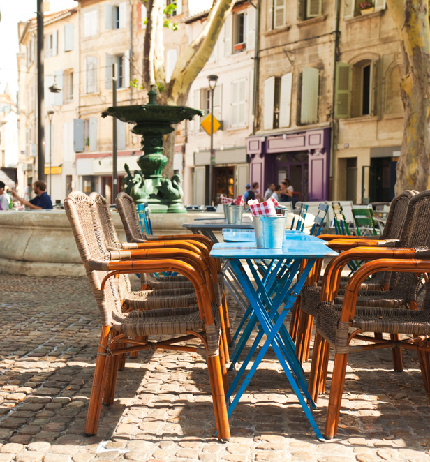 Outdoor restaurant tables in front of fountain in Avignon, France.