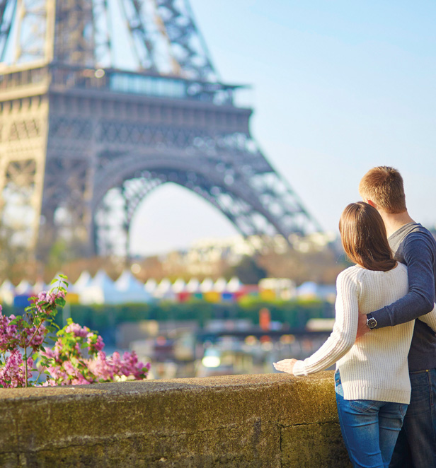 Couple looking up at the Eiffel Tower in Paris, France.