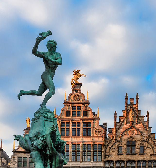 a green statue on top of a fountain in front of a building in Antwerp