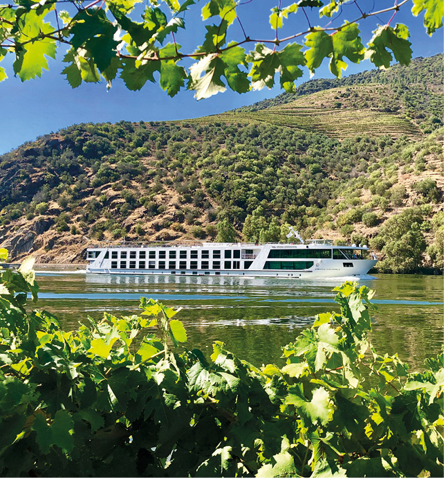 Star-Ship Emerald Radiance cruises through the Douro Valley. Rolling green hills and trees are seen surrounding the ship.